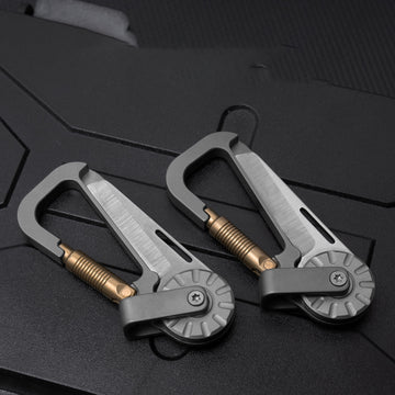Two silver tactical multi-tool carabiners with bronze screws and rotating mechanisms, placed on a dark surface.
